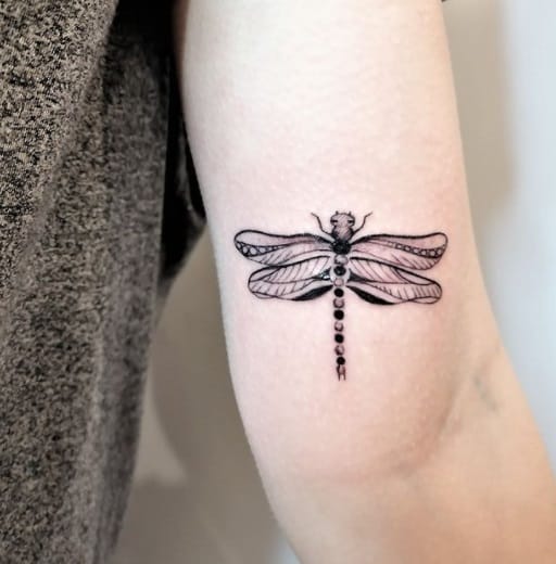 dragonfly on bicep black ink tattoo